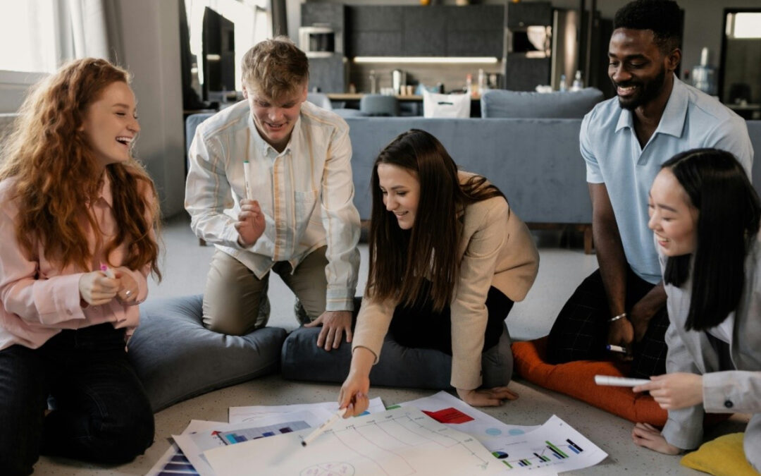 A group of people looking at papers on the floor Description automatically generated